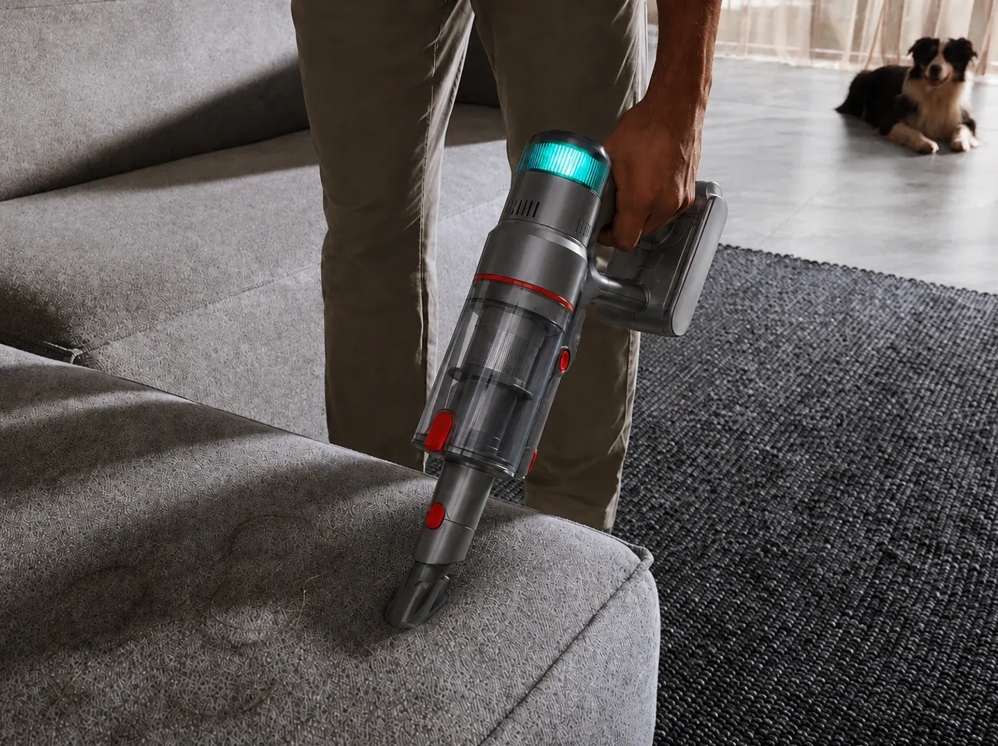 Cleaning a sofa with the Nexam V1 Pro in handheld mode, a dog resting nearby